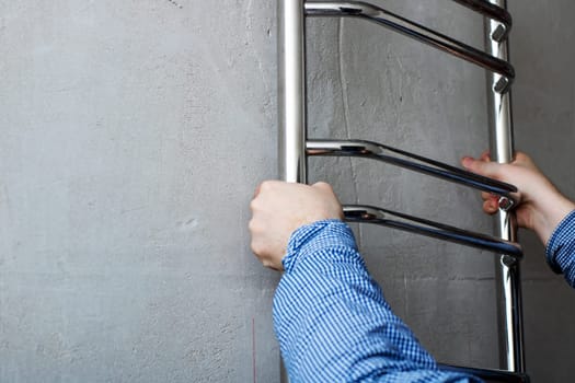 A person is carefully installing a sturdy towel rack securely onto a wall, ensuring it is firmly attached for functional use and aesthetics
