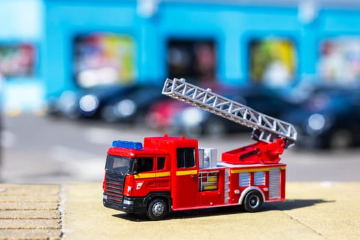 A bright red toy fire truck equipped with a ladder is elegantly positioned on a smooth wooden table, showcasing its vibrant colors and features