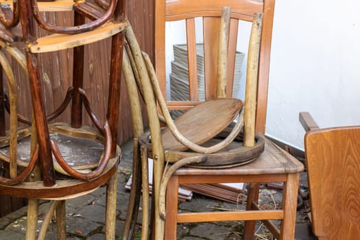 A stack of wooden chairs, although one chair unfortunately has a missing seat, impacting its usability and appearance