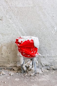 A vibrant red and white object can be seen sitting quietly on the ground in front of a large wall, adding color to the scenery