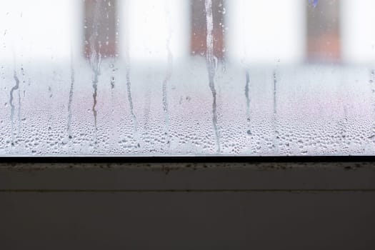 A window that is showing a significant amount of condensation on its surface, creating a blurred and misty view outside