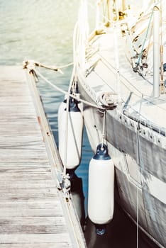Sailboat docked at marina with sunlight, water reflection, wooden pier background, 