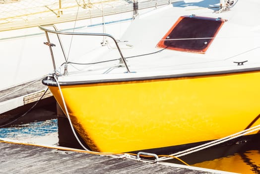Yellow sailboat moored at marina dock with sunlit reflections, background, 