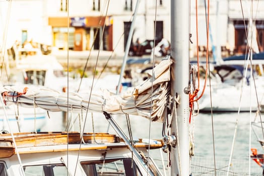 Sailboat mast with ropes in bustling marina on sunny day, background, 