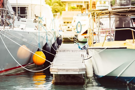 Boats moored at marina with floating dock and ropes, summer travel destination, 