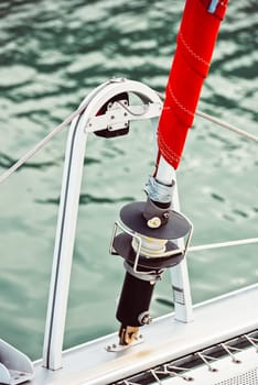 Sailboat rigging and red sail detail against water background, 