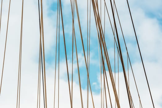Sailboat ropes against blue sky, abstract lines create maritime background 