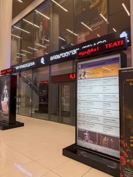 Tbilisi, Georgia, April 12, 2025: Entrance of Griboedov Theater with posters, LED sign and performance schedule inside Galleria building with bright lighting and glass facade