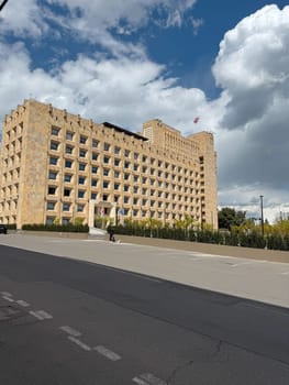 Tbilisi, Georgia, April 6, 2025: Government building in Tbilisi with national and EU flags at the entrance under cloudy sky on sunny day. Politics of Georgia