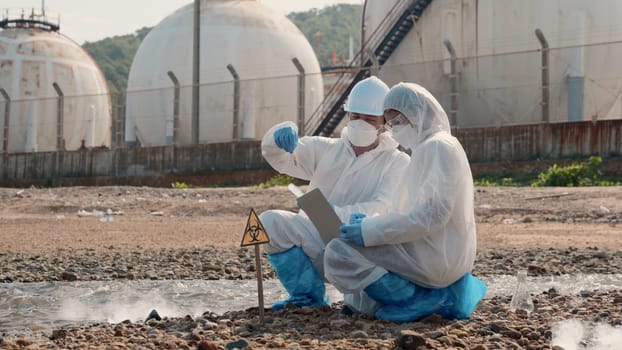 Biologist wear protective suit and mask collects sample of waste water from industry, problem environment, Ecologist sample taken dead fish to inspection and save data to laptop computer, Toxic water