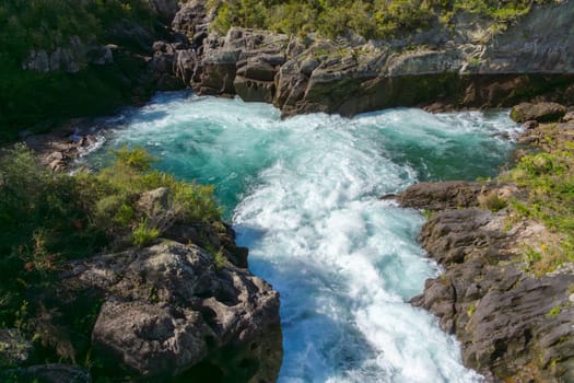 Water surges between rocky ledges into turquoise green pool at Aratiatia, Taupo.