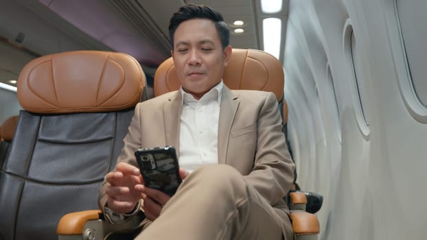 Passenger businessman using mobile phone test wifi connection in plane during flight, Asian man typing smartphone read social and news during business trip travelling