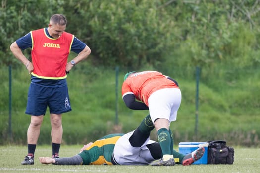 3 may 2025, lisbon. Portugal - oeiras vs ag - medical staff assisting injured rugby player on the field during a match, while coach looks on concerned
