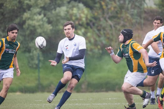 3 may 2025, lisbon. Portugal - oeiras vs ag - rugby players competing in a match on a rainy day, one player kicking the ball