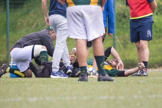 3 may 2025, lisbon. Portugal - oeiras vs ag - medical staff attending to injured rugby player on the field during a rugby match, surrounded by concerned teammates and staff