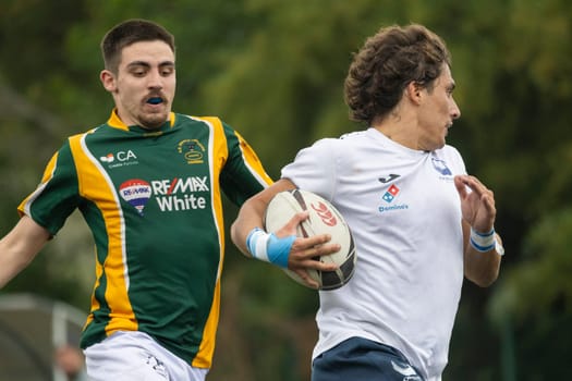 3 may 2025, lisbon. Portugal - oeiras vs ag - rugby player running and holding the ball while being chased by an opponent during a professional game