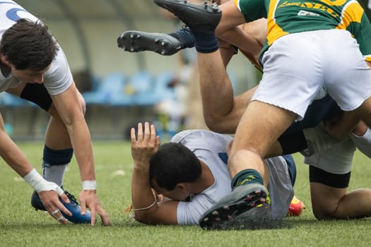 3 may 2025, lisbon. Portugal - oeiras vs ag - rugby players tackling and falling on the grass during a competitive rugby match