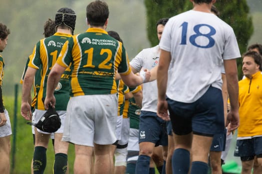 3 may 2025, lisbon. Portugal - oeiras vs ag - rugby players shaking hands after a match on a rainy day, showing sportsmanship and fair play