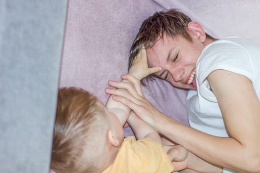 Teenage boy happily playing with his younger brother while looking after him. High quality photo