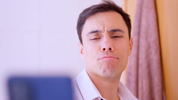 Businessman making a funny face while taking a selfie with his smartphone in a bathroom mirror