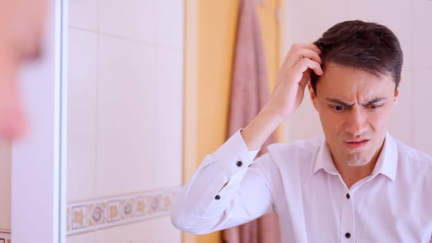 Worried businessman scratching head while looking at his reflection in the mirror