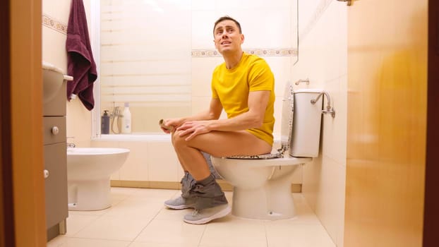 Man realizing he has finished toilet paper roll while sitting on toilet