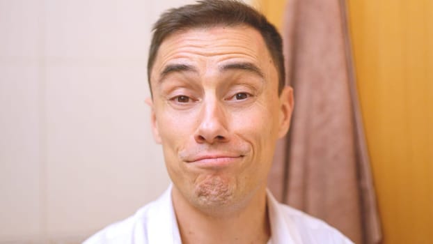 Close up of a friendly man making a funny, slightly embarrassed expression in a bathroom setting