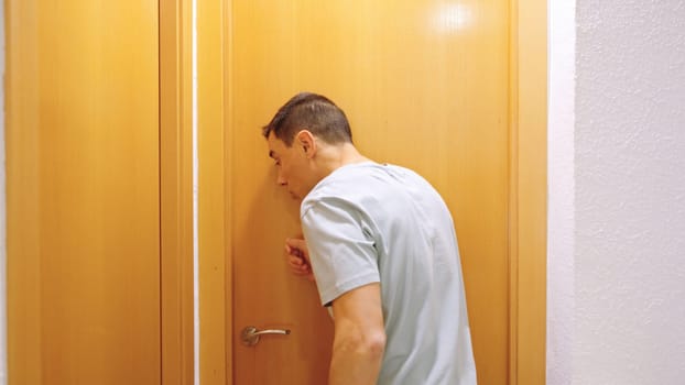 Man at bathroom door, waiting impatiently for someone to finish using it