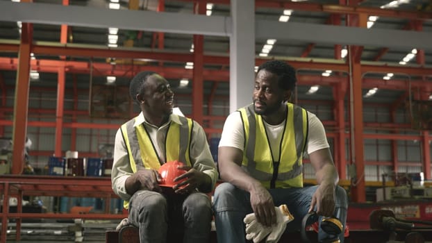 Tired worker man sit in warehouses worried taking break with friend from hard work thinking of production problems at factory, colleague encourage, engineering working in heavy industry factory