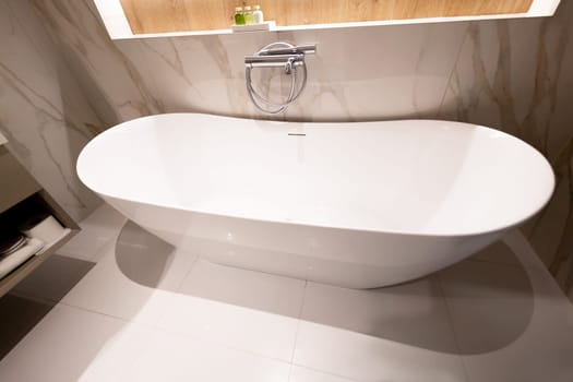 A modern freestanding white bathtub in a clean and elegant luxury bathroom interior.