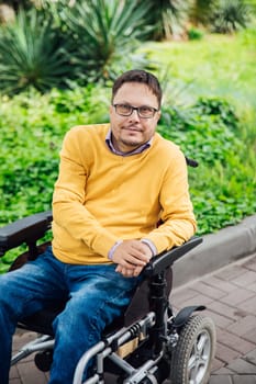 A man with disabilities in a wheelchair walks alone in the park