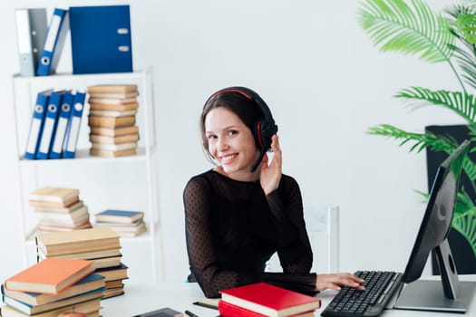 Woman in business suit working online in headphones at computer