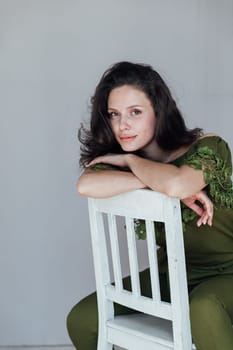 Brunette woman smiling sitting on a chair in a room by the window