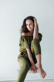 Brunette woman smiling sitting on a chair in a room by the window