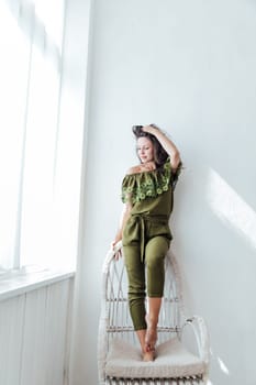 Brunette woman smiling sitting on a chair in a room by the window