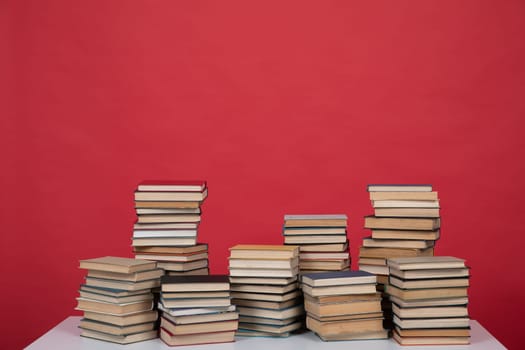 Stacks of educational books on the red background of the university library
