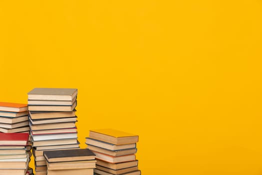 Stacks of old educational books for teaching in the library on a yellow background at school
