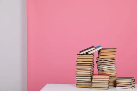 Stacks of old educational books for teaching in the library on a pink background at school