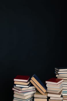 Stacks of old educational books for studying in the library on a black background of the university