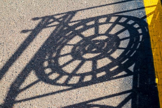 Shadow casting from the metal decorative fence to the asphalt