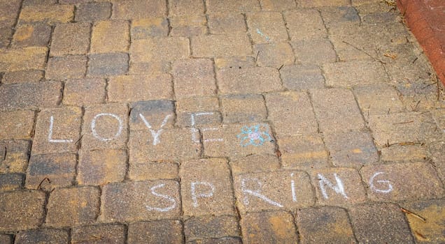 Kids drew the words love, spring on the pavement with colored chalks
