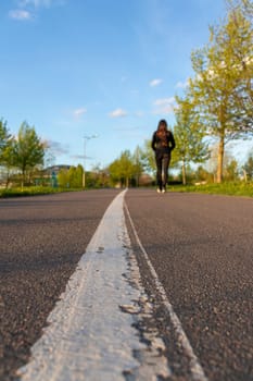 Asphalt surface of the jogging trail with painted dividing lane. Woman walking