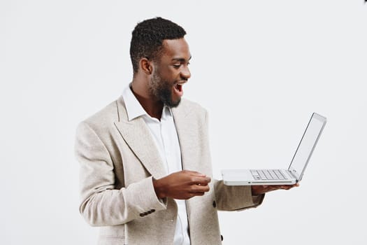 Cheerful young African American man dressed in business casual clothing, holding an open laptop and smiling broadly, standing against a plain white background. Concept: innovation, remote work, digital communication, achievement, positivity, modern professional.
