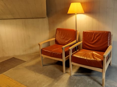 Two brown leather chairs sit side by side, illuminated by a warm lamp in a contemporary room. The simple design enhances the inviting atmosphere of the space.