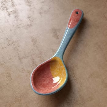 Colorful ceramic spoon on a textured background