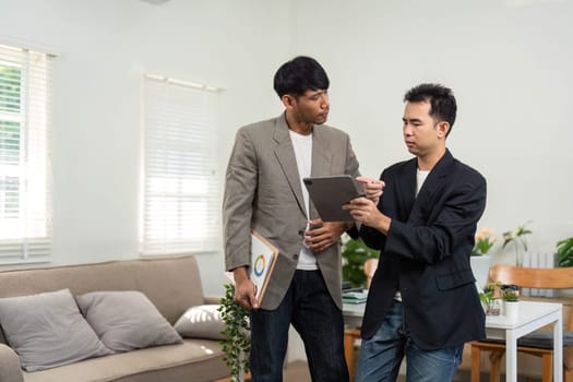 In a contemporary office, two business partners engage in a strategic meeting, discussing project details and analyzing data.