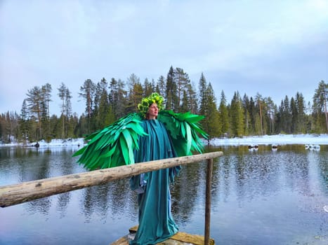 A girl in a green dress stands by the lake, embodying spring with a fantasy theme during a tranquil role-playing session amidst nature.