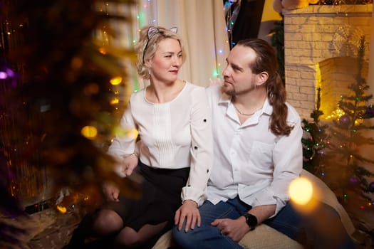 A couple celebrates Christmas and the New Year surrounded by festive decorations in their cozy home.