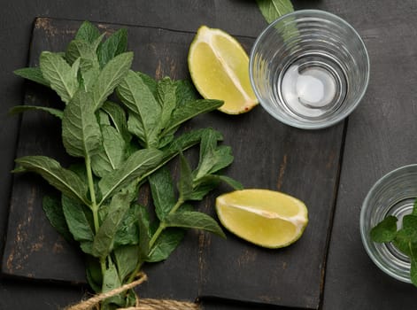 Bunch of fresh green mint, lime slices, glasses, top view. Cocktail ingredient