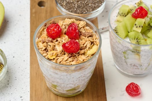Yogurt and chia seed pudding in a glass, kiwi pieces. White table, top view